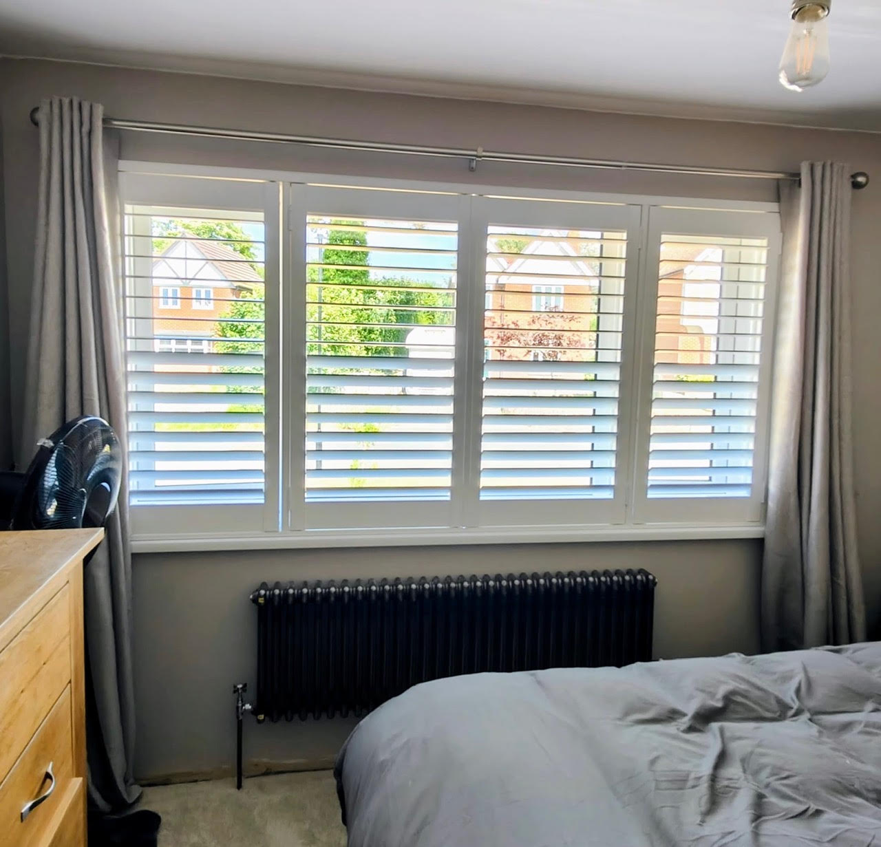 Full Height shutters in a bedroom framed by grey curtains
