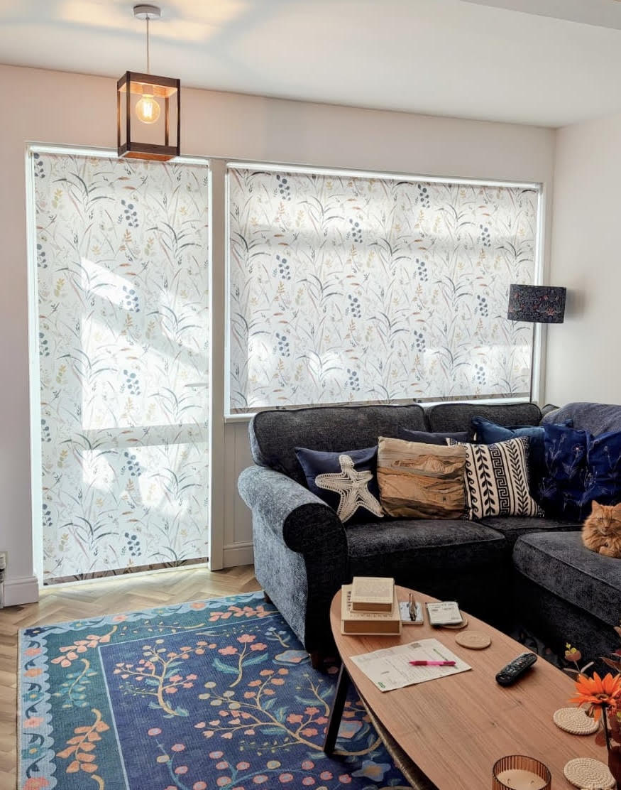 Delicate meadow-print roller blinds in a cosy living room