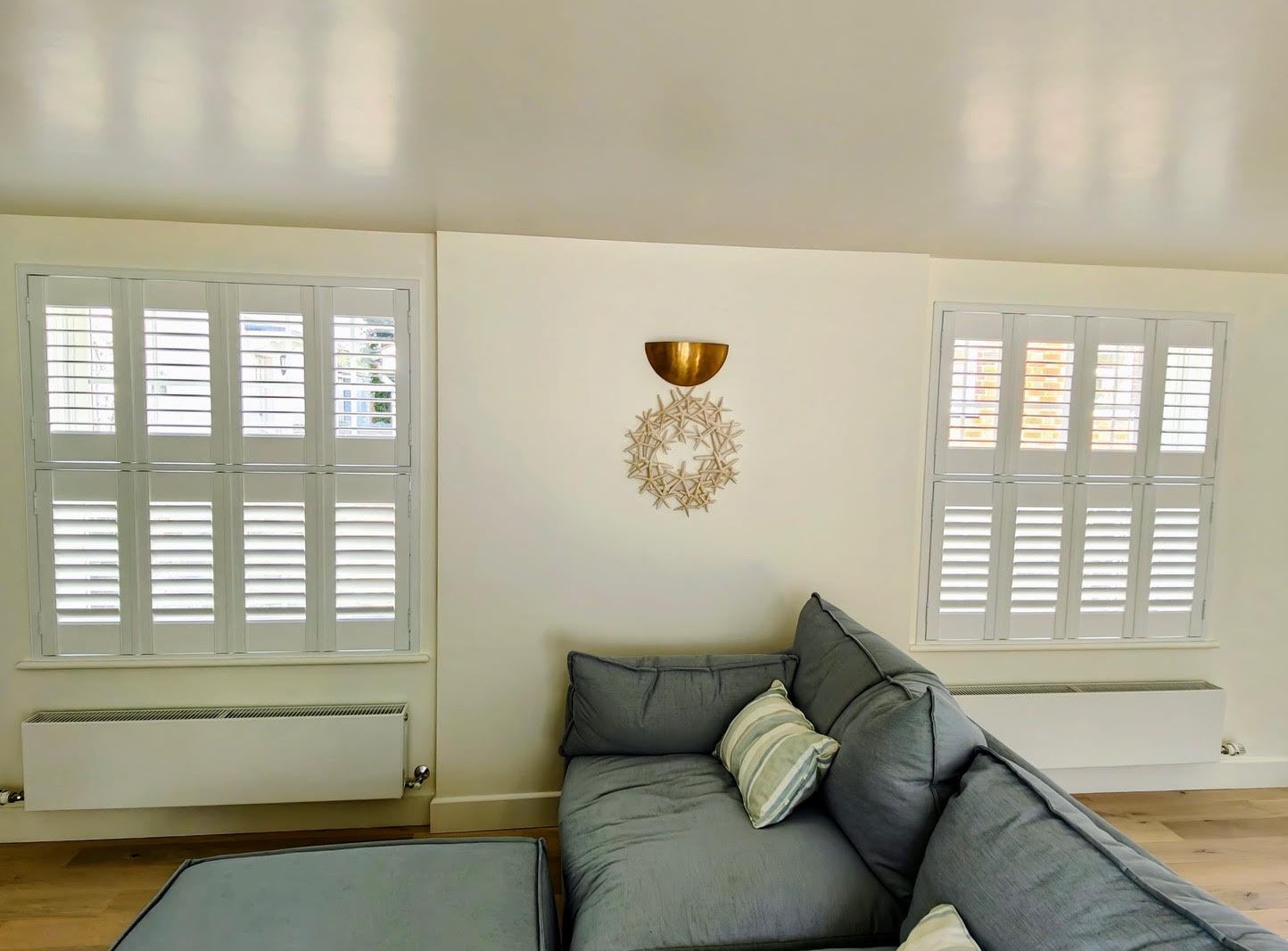 Twin Tier-on-Tier shutters in a light living room with grey sofa