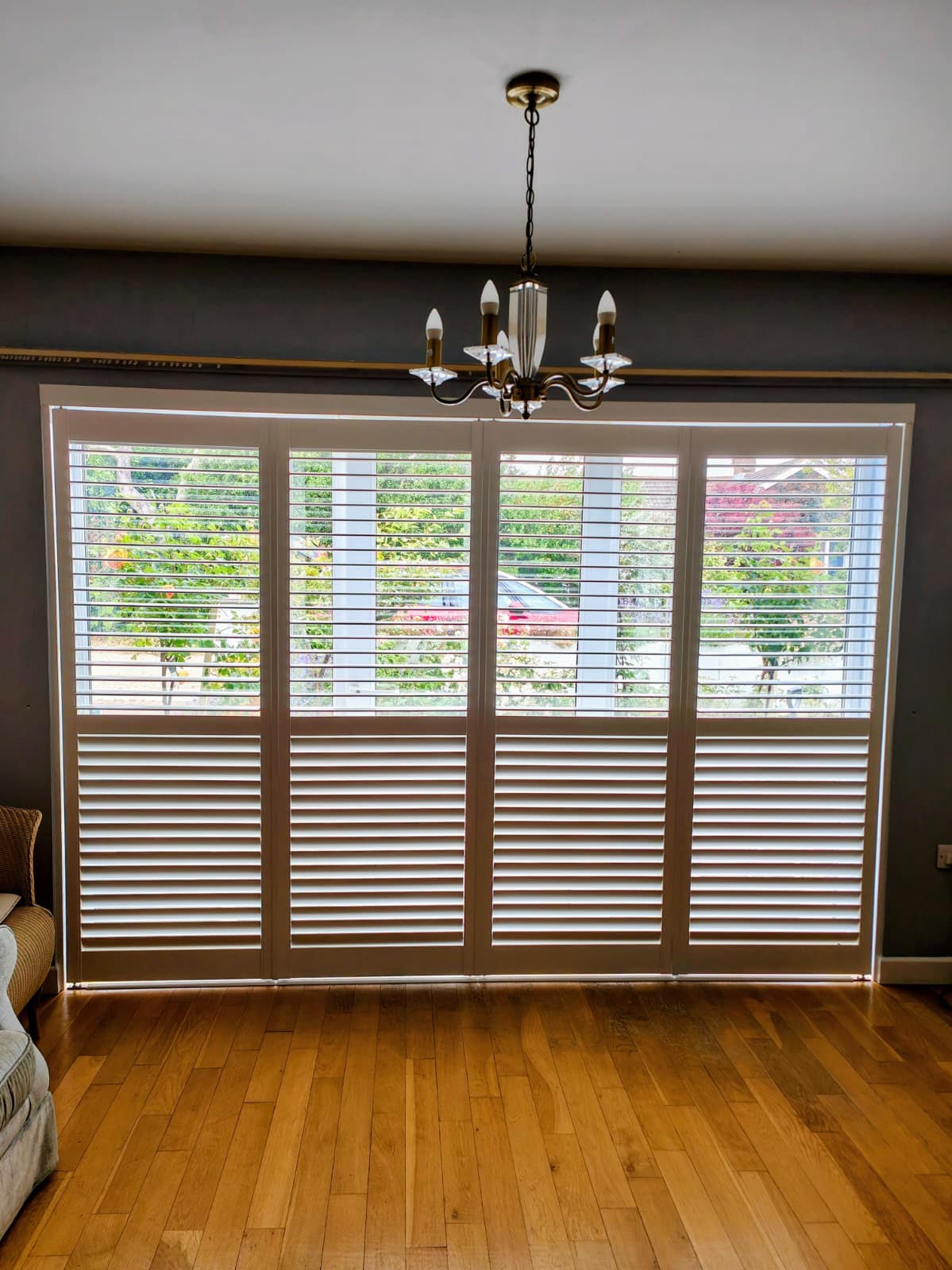 White tracked shutters spanning a wide bi-fold opening in a modern living room