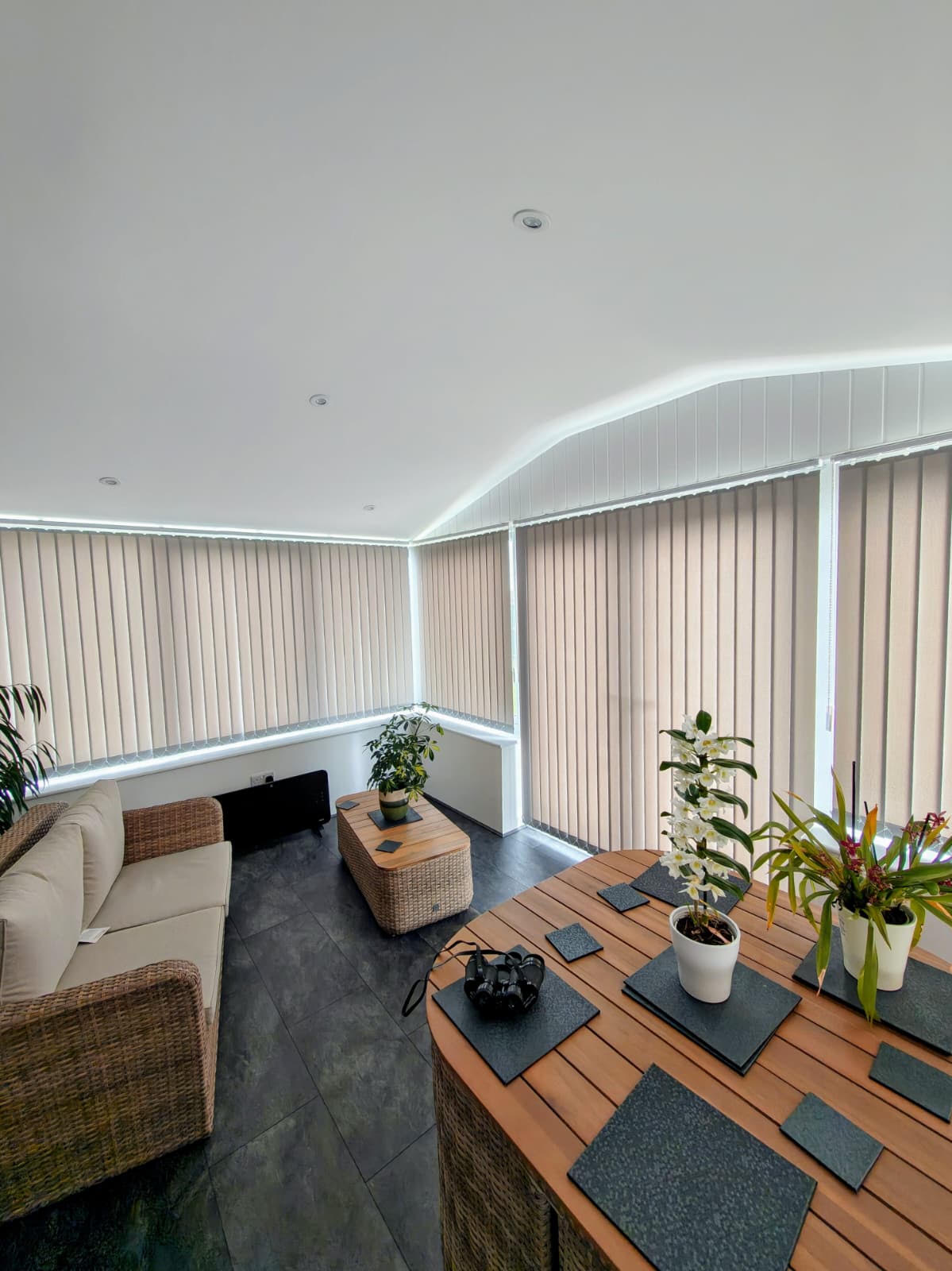 Neutral vertical blinds wrapping a bright garden room