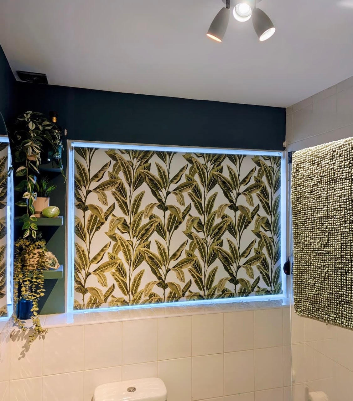 Botanical patterned roller blind in a dark green bathroom