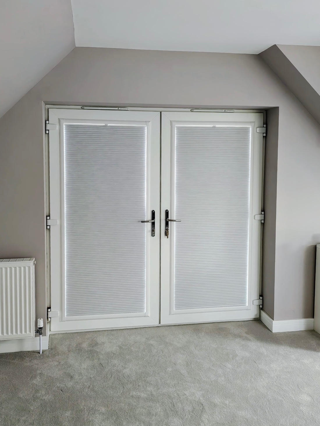 White pleated Perfect Fit blinds on French doors in a loft bedroom