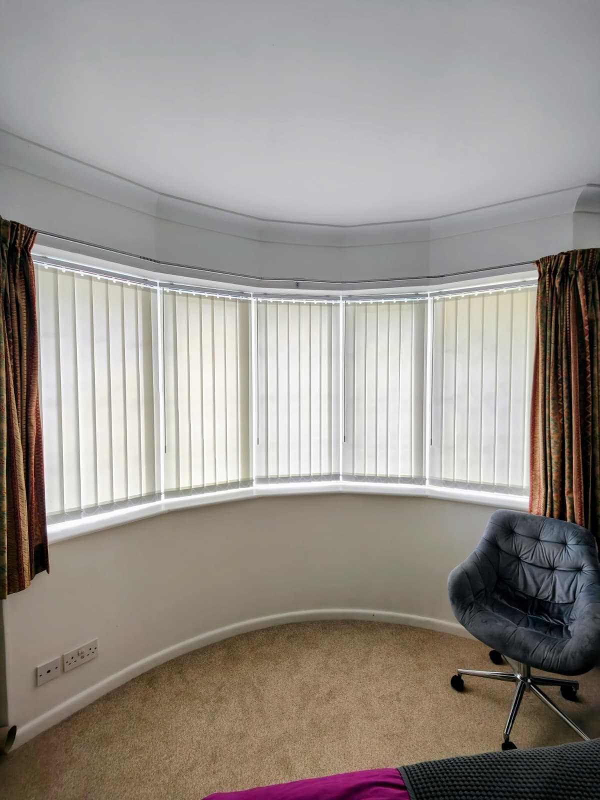 Cream vertical blinds across a curved bay window