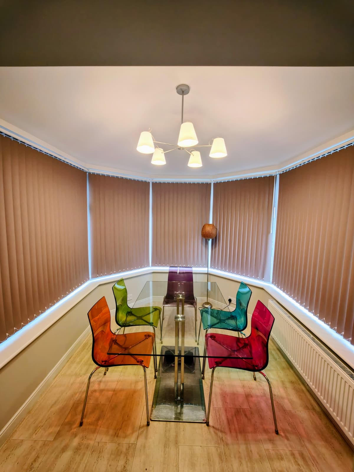 Dusky pink vertical blinds fitted around a bay dining room