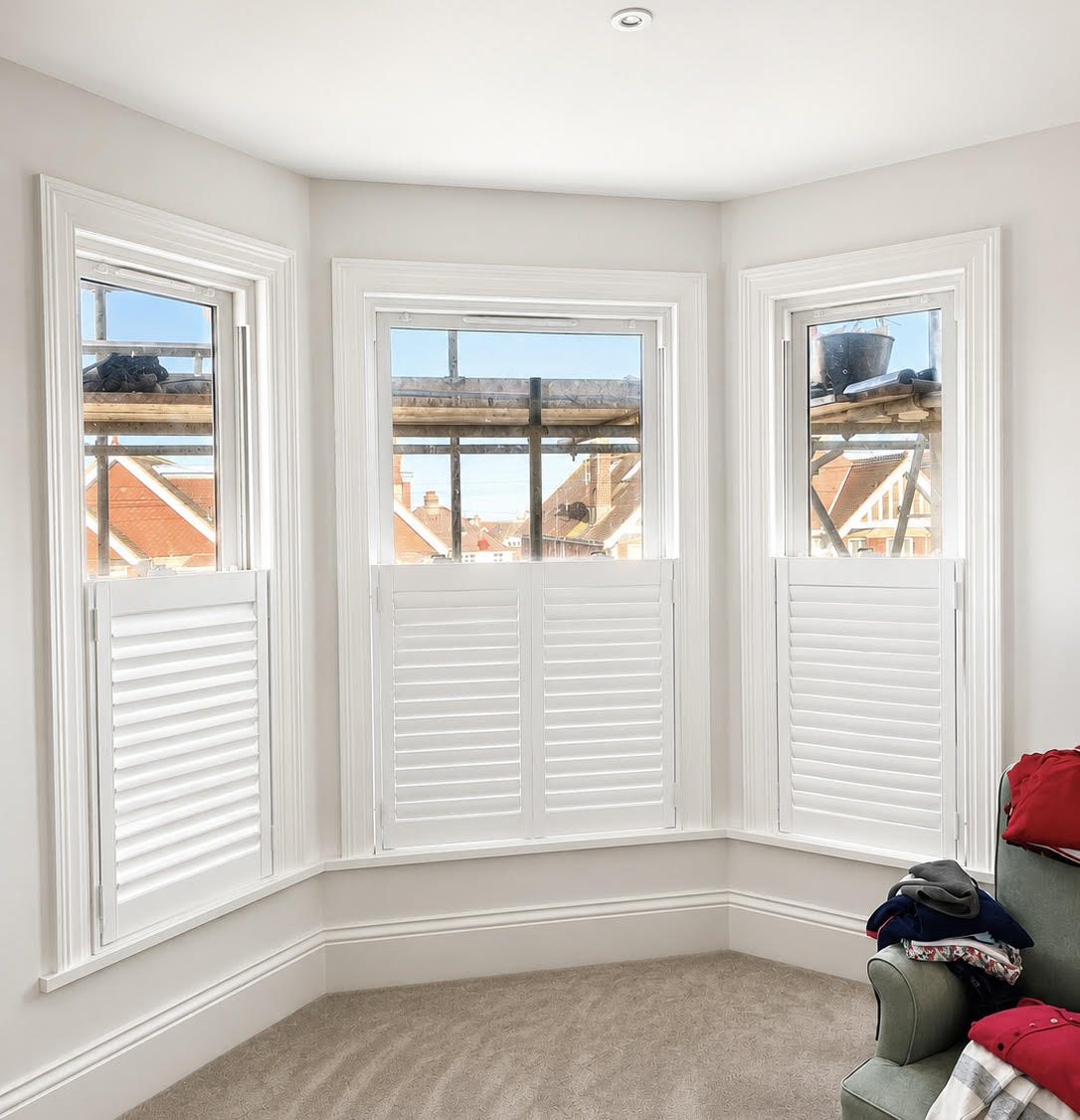 Café Style shutters across three bay windows in a bright bedroom